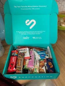 a teal box with an assortment of snacks sitting on a countertop